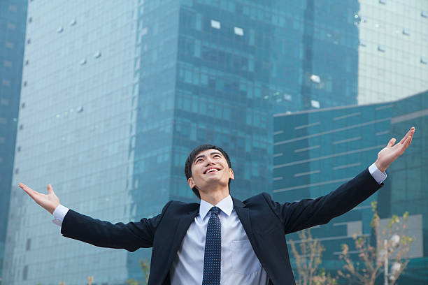 istock Young businessman smiling and standing outside with arms outstretched 450035567