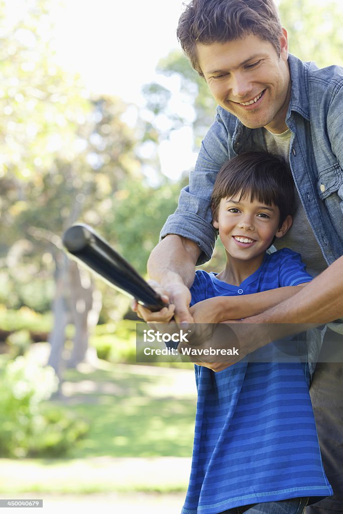 The training son and dad smile while swinging The dad teaches his son how to swing the baseball bat 30-39 Years Stock Photo