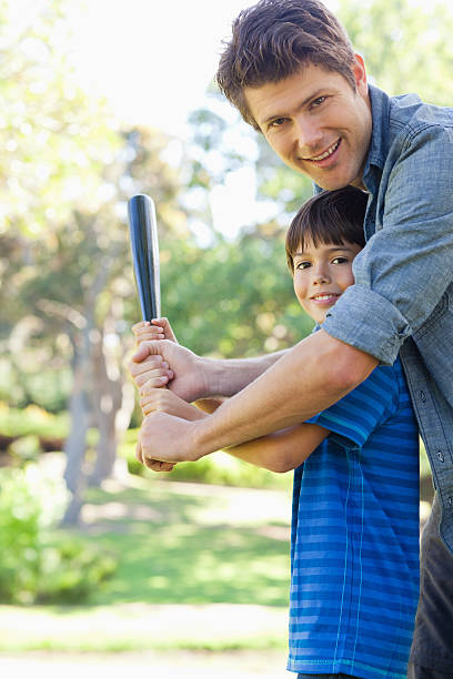 istock Smiling father helps his son hit a home run 450040785