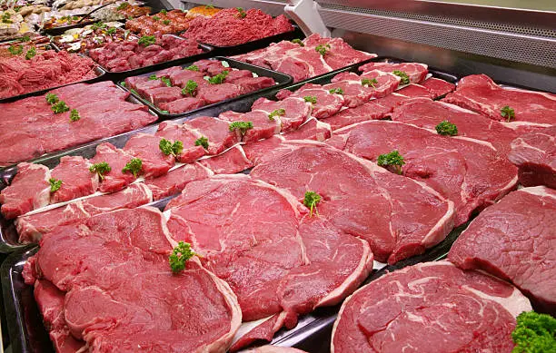 A selection of raw  beef in a refrigerated counter.