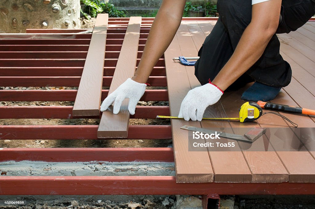 Travailleur en installant parquet en bois pour patio - Photo de Terrasse en bois libre de droits