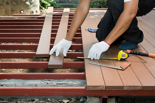 Worker installing wood floor for patio