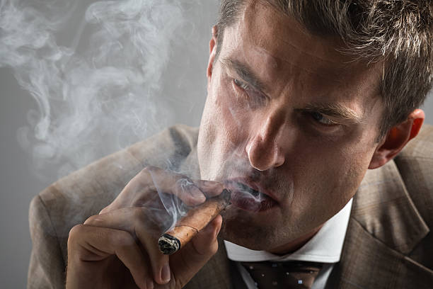 istock hard gaze businessman while smoking a cuban cigar 450076367