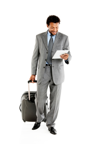 Happy mature african business executive with luggage looking at digital tablet while walking over white background