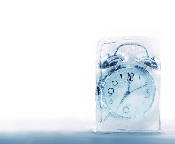 An alarm clock frozen in a block of ice stock photo