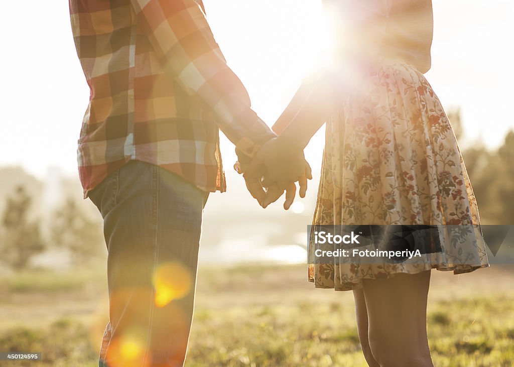 Young couple in love. Young couple in love walking in the autumn park holding hands looking in the sunset Adult Stock Photo