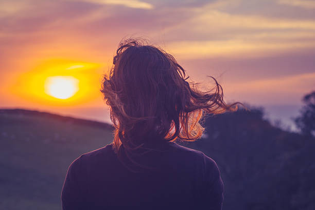 istock Young woman admiring the sunset over fields 450136921