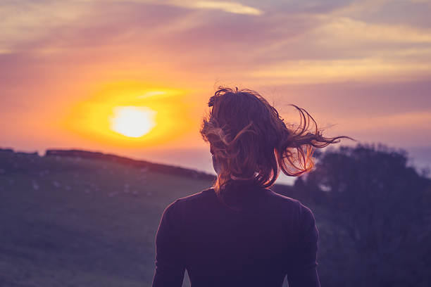 istock Young woman admiring the sunset over fields 450137535