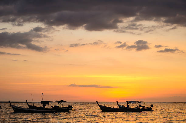 istock Silhouette boat at beach and sunset 450140945