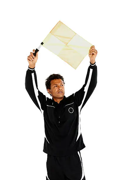 Soccer referee in black jersey holding up a official flag over white background