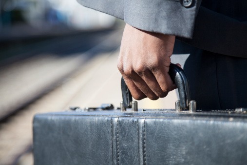Close-up of an african businessman holding his briefcase at the train stration in Cape Town, South Africa.