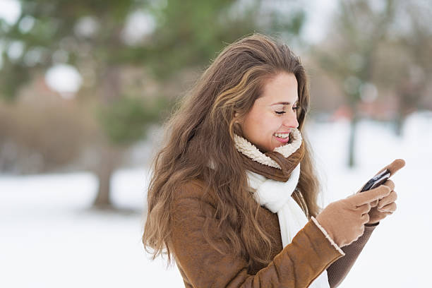istock Happy young woman writing sms in winter park 450156979
