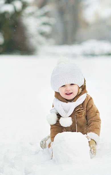 istock Happy baby making snowball for snowman 450158241