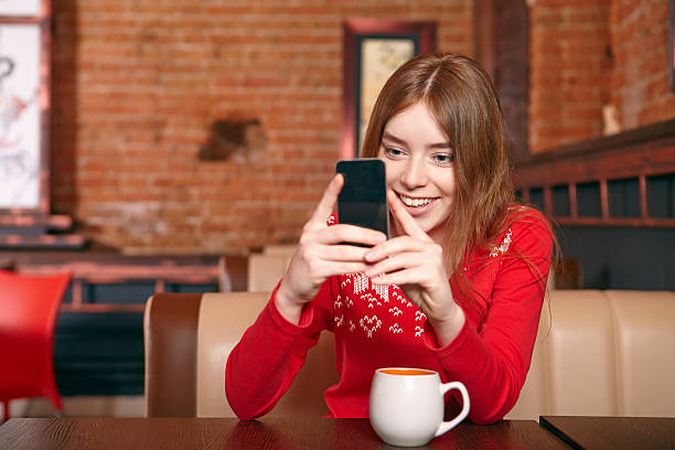 belle fille soulever sms sur téléphone mobile au café. - red text messaging cafe teenage girls photos et images de collection