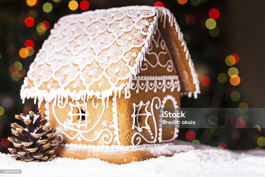 gingerbread house gingerbread house over defocused lights of Chrismtas decorated fir tree Baked Stock Photo