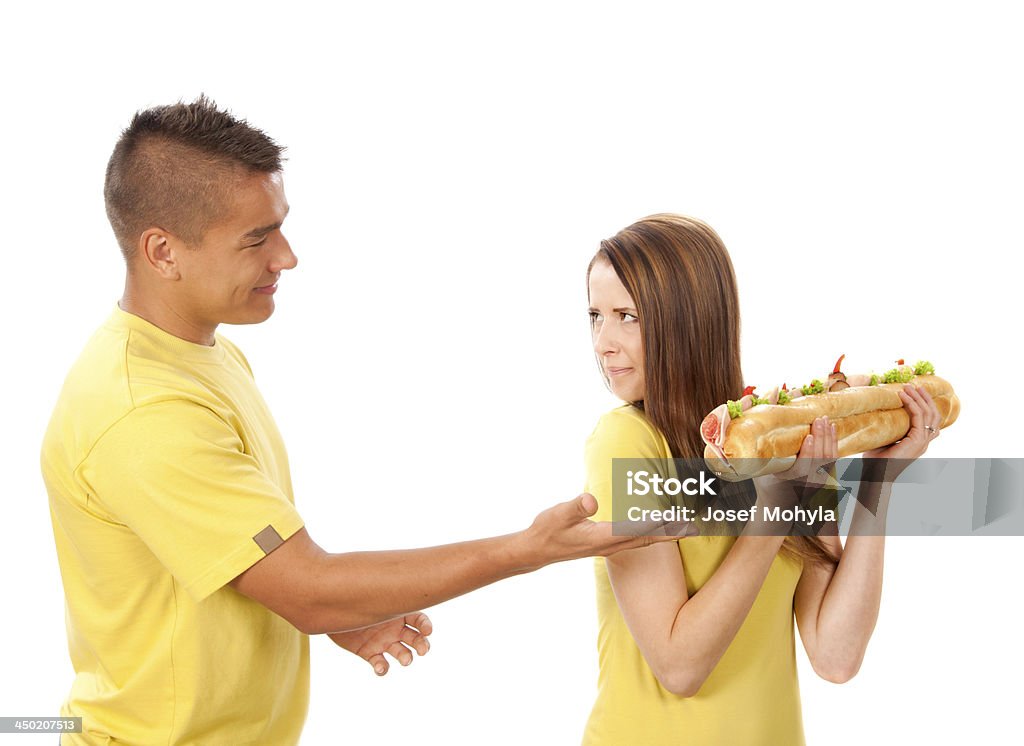 Young  woman and man play with big baguette Young  woman and man play with great sandwich. Great baguette with salami, cheese, egg and pepper, white background, selective focus. 18-19 Years Stock Photo