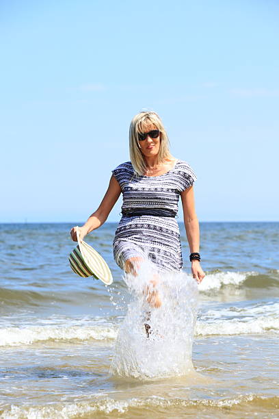 istock mature woman on beach summer holiday 450219835