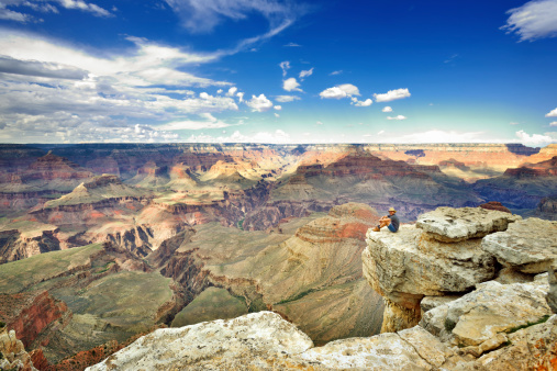 Young man sitting on a rock at the edge of the Grand Canyon.