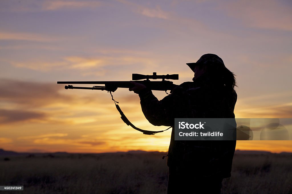 Woman Hunter Shooting at Sunset a woman hunter shooting her rifle silhouetted at sunset Hunting - Sport Stock Photo