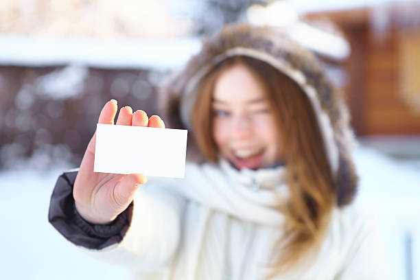istock Young beautiful girl with blank visiting card. Winter. 450250795