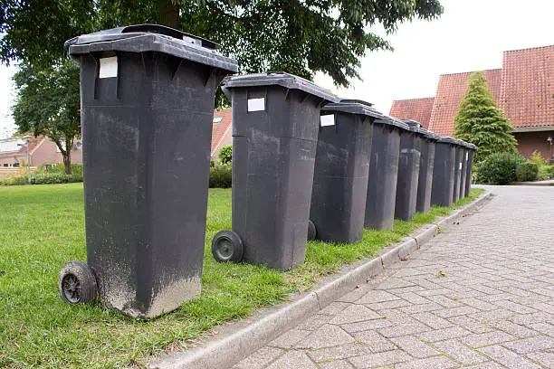 Photo of Grey garbage containers in a row