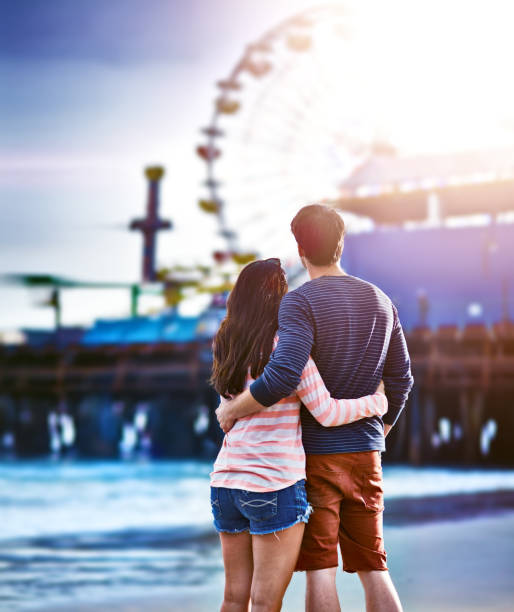 istock Romantic couple looking at Santa Monica pier from the beach 450252575