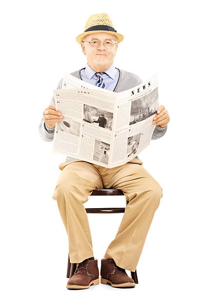 istock Senior gentleman on chair holding a newspaper 450268797