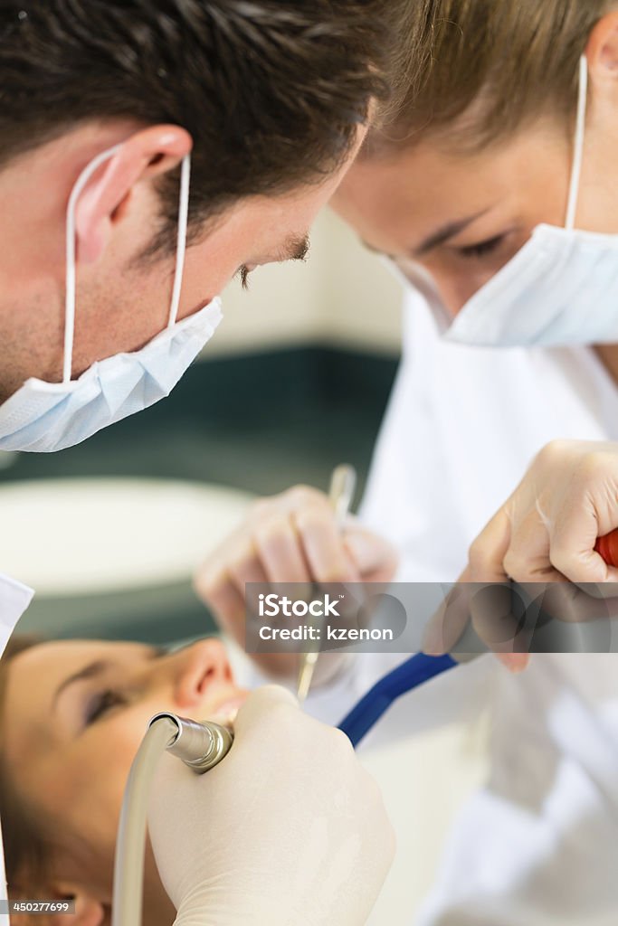 Patient with Dentist - dental treatment Female patient with dentist and assistant in a dental treatment, wearing masks and gloves Dental Assistant Stock Photo