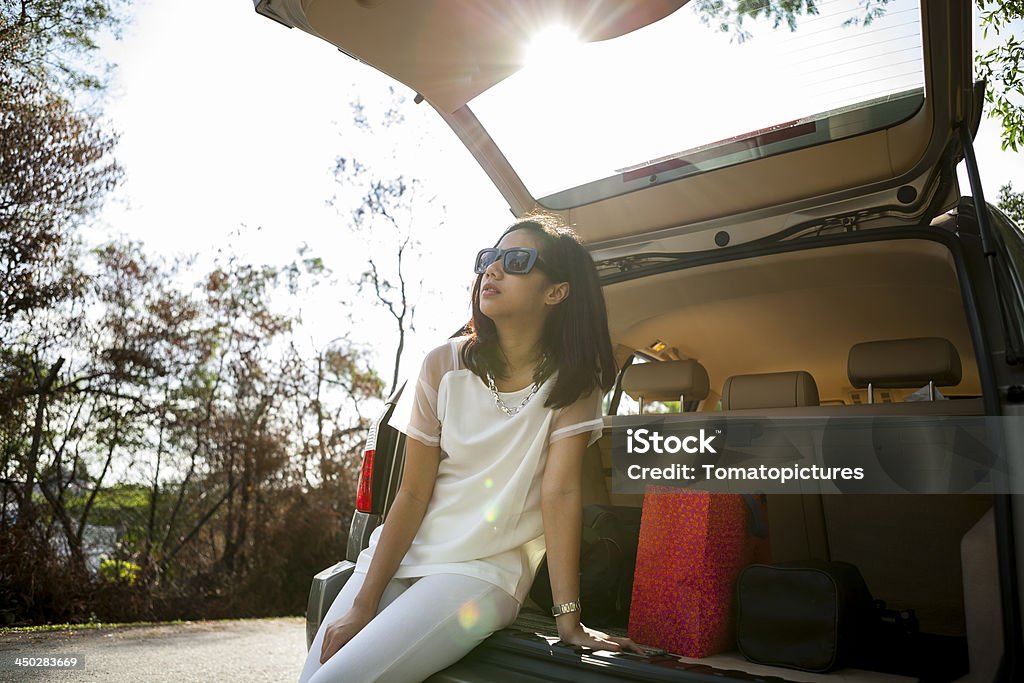 Felice donna attraente con occhiali da sole seduti in SUV di trunk - Foto stock royalty-free di Adulto