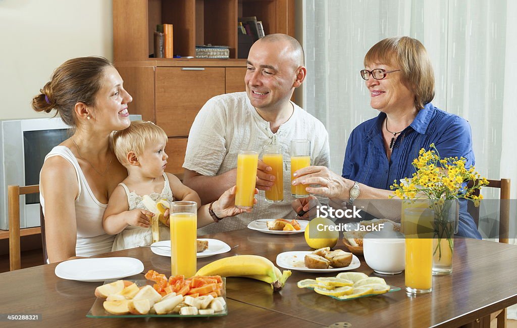 Friuts and juice Smiling multigeneration family  eating friuts with juice at home together Active Seniors Stock Photo
