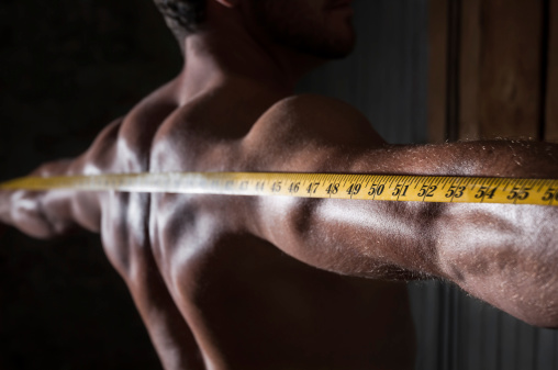 A stock photo of a man's strong muscular back with a tape measure