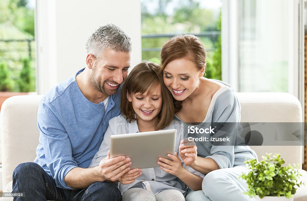 Happy family with digital tablet Happy mother, father and their daughter using a digital tablet.  10-11 Years Stock Photo