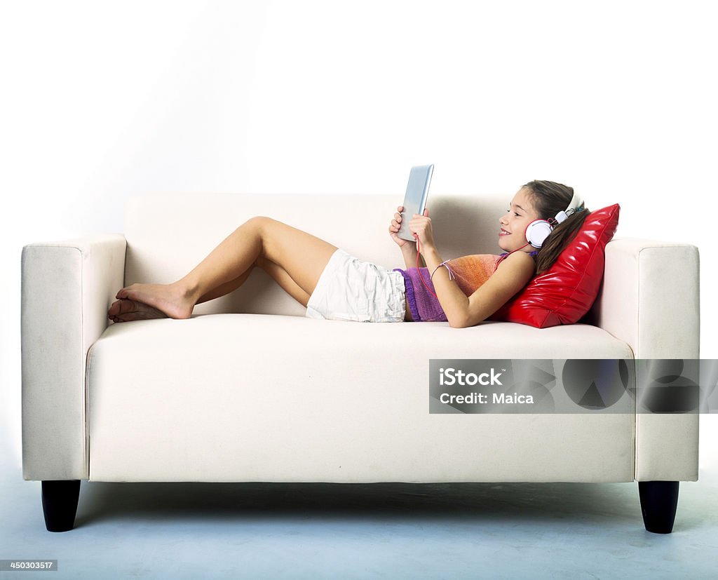 Child with digital tablet Ten years old in a sofa, watching and listening from her digital tablet. Girls Stock Photo