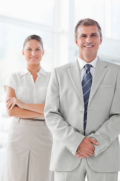 istock Businessman standing indoors with secretary behind him 450304839