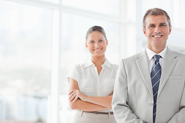 istock Smiling businessman standing with secretary behind him 450304981