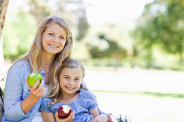 istock Smiling mother and daughter showing apples 450305081