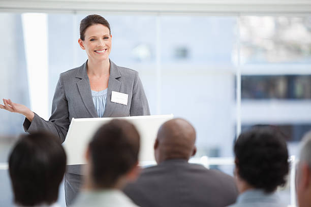 istock Smiling businesswoman gesturing while the colleagues watch her 450308401