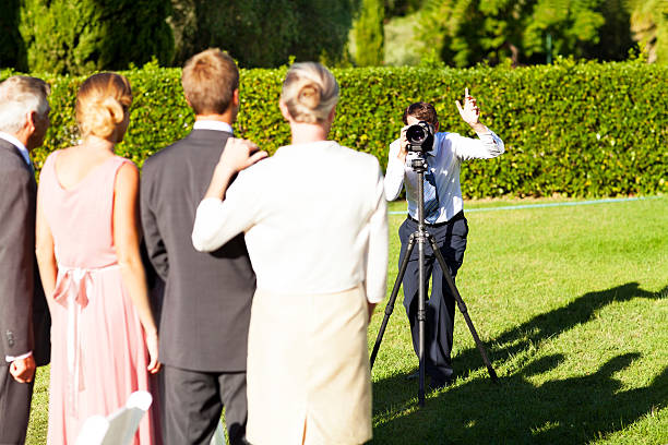 Family Posing While Man Photographing Them At Garden Wedding