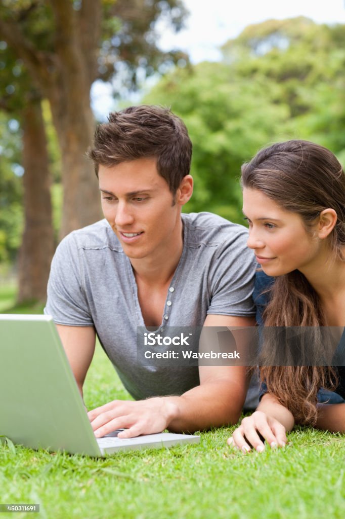 Primer plano de una pareja usando la computadora portátil mientras están recostadas - Foto de stock de 18-19 años libre de derechos