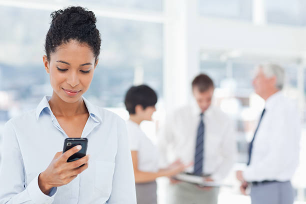 istock Saleswoman reading text message with colleagues behind her 450311803