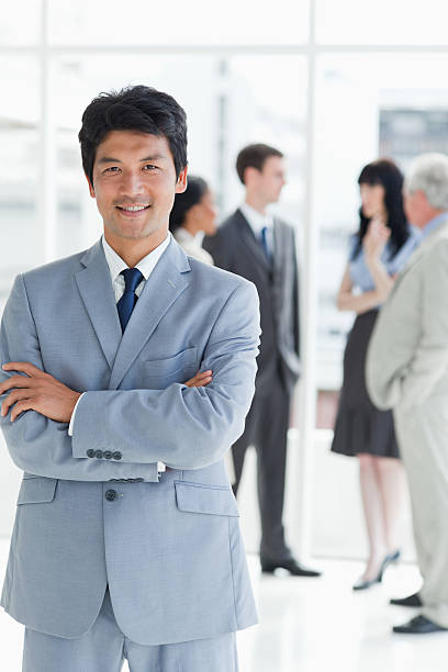 istock Smiling executive crossing arms with his team behind 450312167