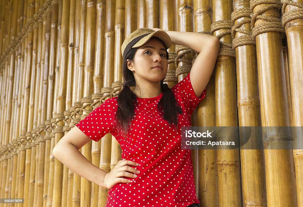 Bellissima giovane donna appoggiato su una parete di bambù - Foto stock royalty-free di 20-24 anni