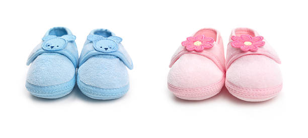 Two pairs of baby boy and girl shoes Closeup of cute pink and blue baby boy and girl shoes isolated on white background baby booties stock pictures, royalty-free photos & images