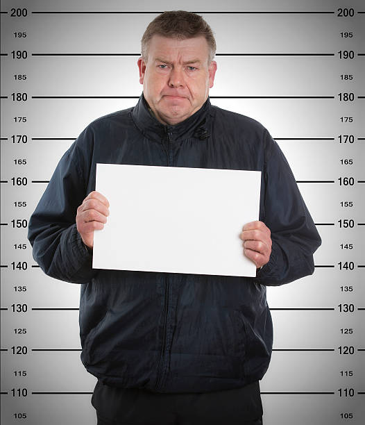 istock mugshot - young man arrested and  holding a  blackboard 450324941