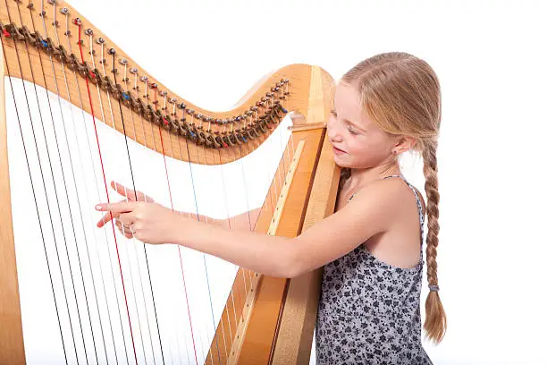 young girl in blue playing harp against white backgound