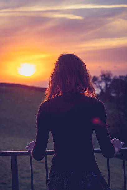 istock Woman admiring sunset from her balcony in countryside 450366151