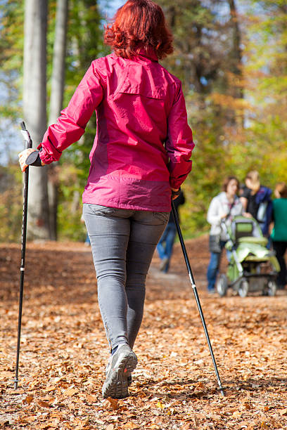 スポーティブかわいい女性ノルディックウォーキング秋のクロスカントリー - middle human age leaf tree ストックフォトと画像