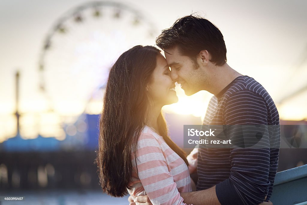 romantic couple embracing  at sunset photo of a romantic couple  embracing  at sunset in front of santa monica ferris wheel. Adult Stock Photo