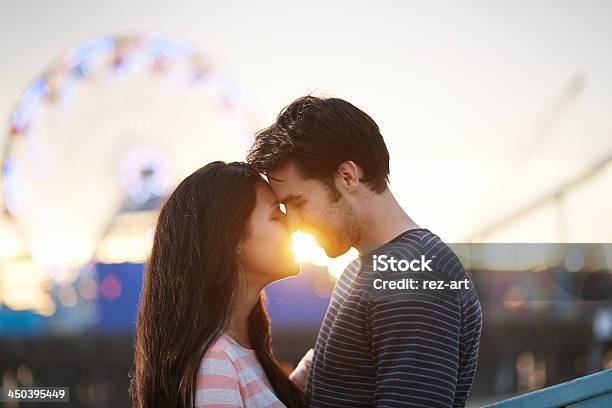 Smiling Man And Woman Embracing At Sunset At A Carnival Stock Photo - Download Image Now