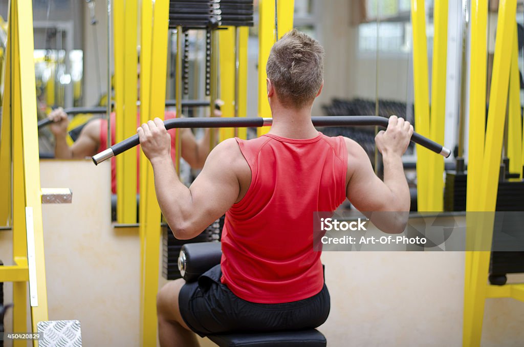 Atractivo joven haciendo ejercicios en el gimnasio con equipos - Foto de stock de Adulto libre de derechos